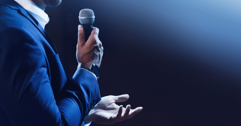 Medical staffing professional delivering a confident speech on stage with a microphone.