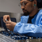 Sterile processing technician inspecting surgical instruments in a sterile environment.