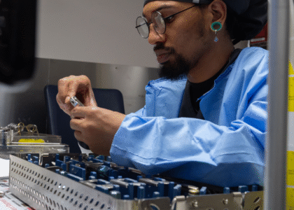 Sterile processing technician inspecting surgical instruments in a sterile environment.
