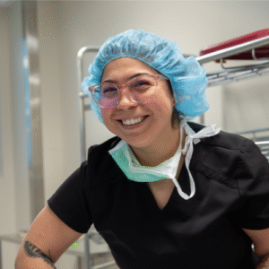 Smiling healthcare worker in scrubs and cap.