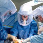 Surgeons performing surgery in protective gear.