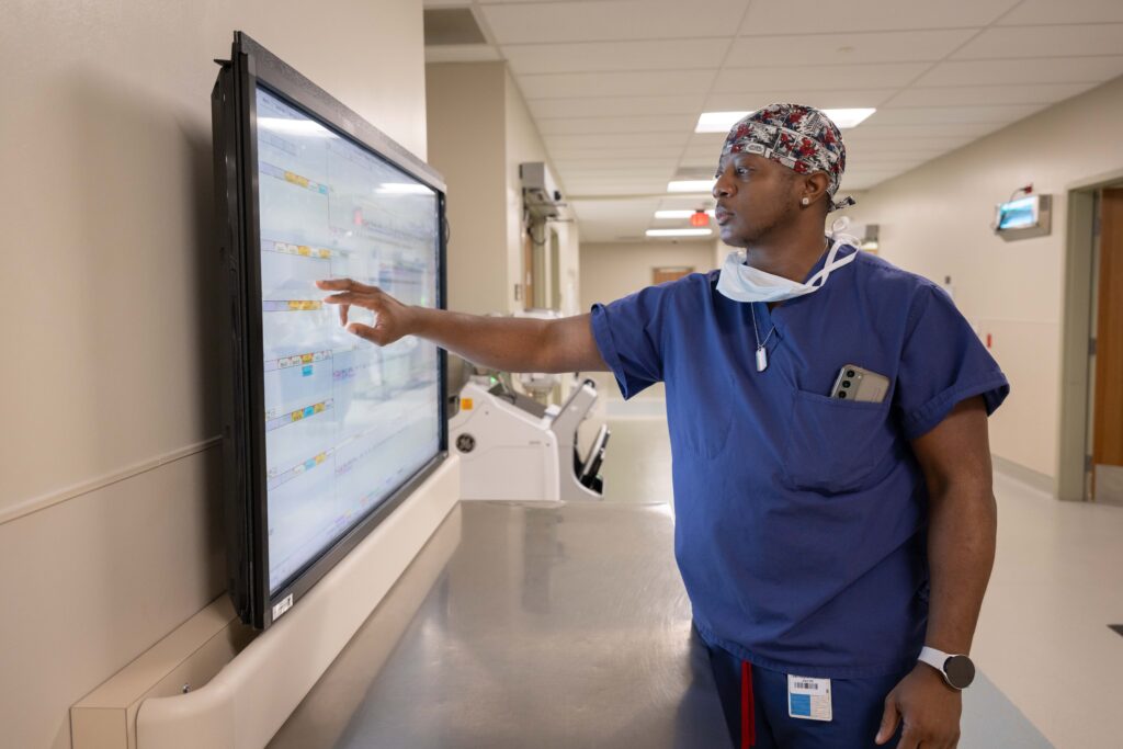 Medical professional interacting with touchscreen in hospital.