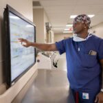 Medical professional interacting with touchscreen in hospital.