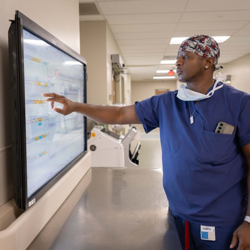 Medical professional interacting with touchscreen in hospital.