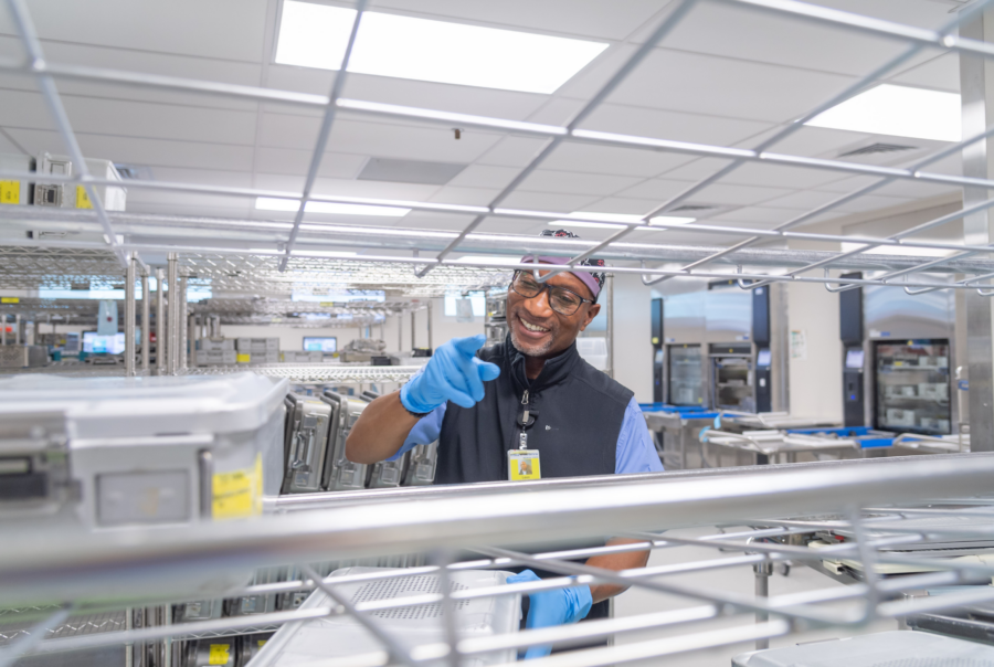 Sterile processing technician handling surgical instrument trays in a hospital SPD department during sterile processing and workflow operations.